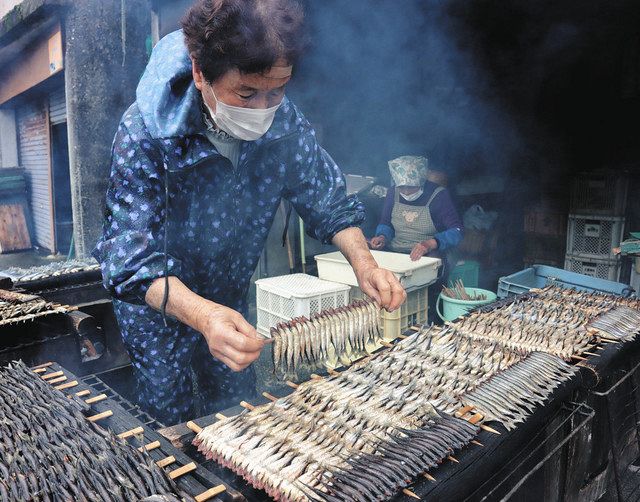 小サバの「あぶり」を作る浜中さん（左）＝尾鷲市梶賀町で 