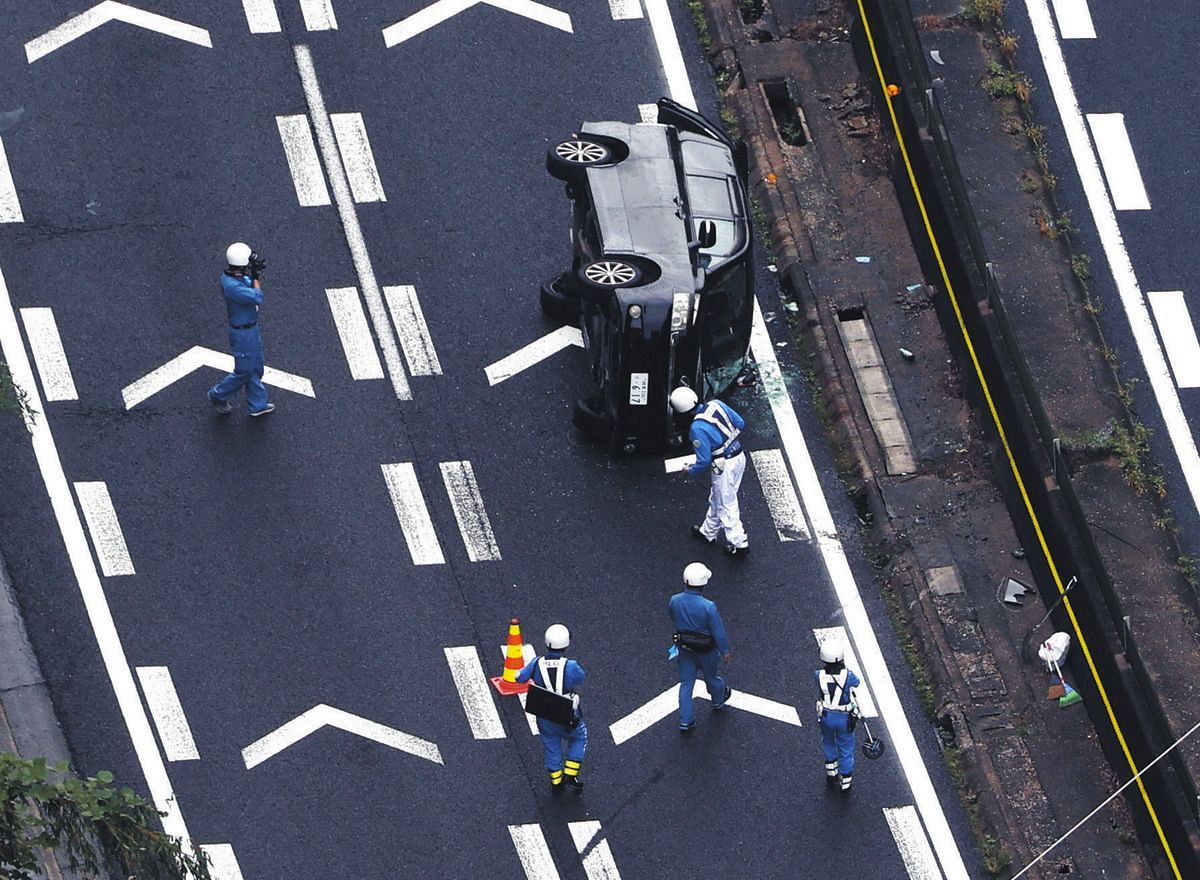 事故で横転した乗用車を調べる警察官＝25日午後、岐阜県瑞浪市で、本社ヘリ「わかづる」から
