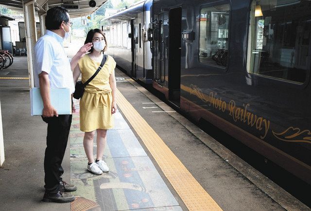 田島義久総務部長（左）から観光列車の案内を受ける山田恵さん＝穴水町の穴水駅で 