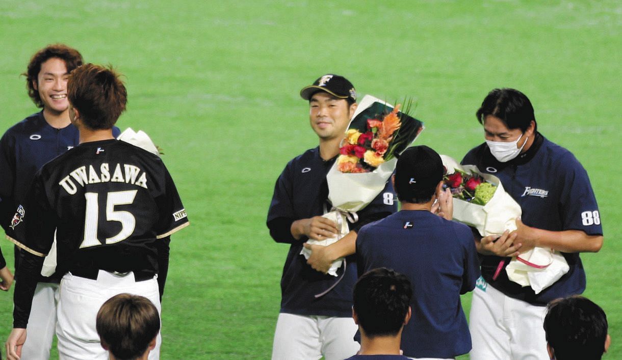 練習開始前に東京五輪での金メダル獲得を祝う花束を受け取り笑みを見せる日本ハム・近藤健介外野手（中央）
