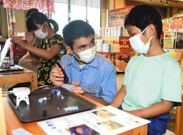 高校生（中）に教わりながらストラップを作る子どもたち＝鳥羽市安楽島町の鳥羽ビューホテル花真珠で 