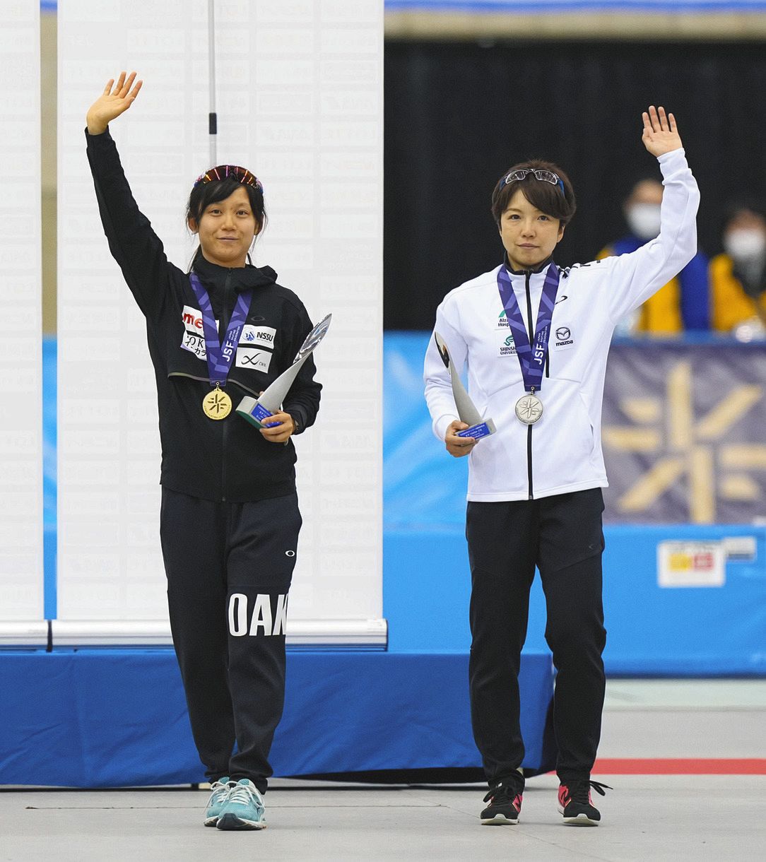 女子１５００メートルの表彰式を終え、観客席に向かって手を振る優勝の高木美帆（左）と２位の小平奈緒