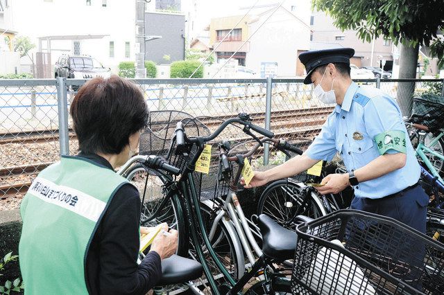 盗難被害防止の対策などが書かれた紙を自転車にくくり着ける署員ら＝岐阜市長住町で