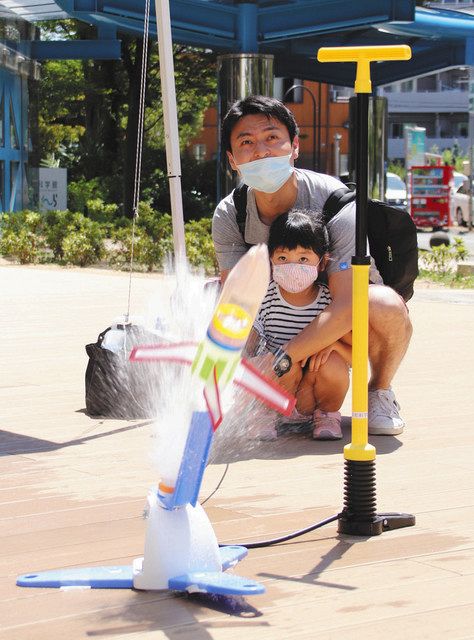 水しぶきを上げて飛び出すペットボトルロケットに驚く親子=浜松市中区の浜松科学館で
