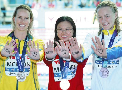世界水泳の女子１００メートルバタフライの表彰式で、メダルを獲得した３選手は「NEVER GIVE UP　Rikako」と、池江璃花子へのメッセージを手に書いて登場＝2019年7月