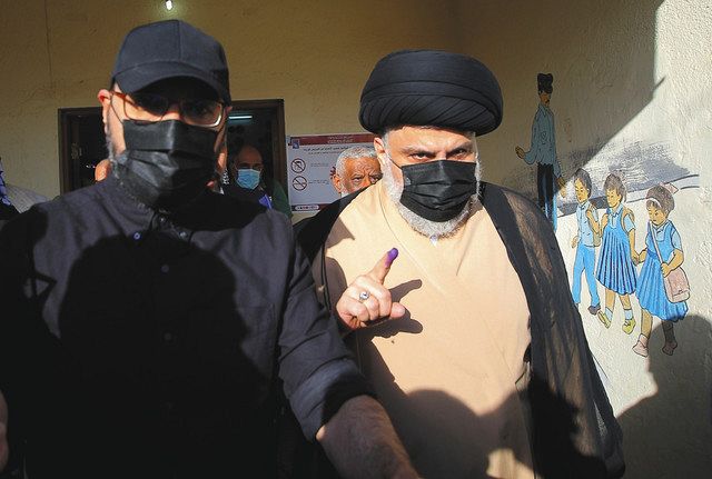 イラク中部ナジャフで１０日、投票を終えたことを示すインクの付いた指を見せるイスラム教シーア派指導者のサドル師（右）＝ＡＰ

