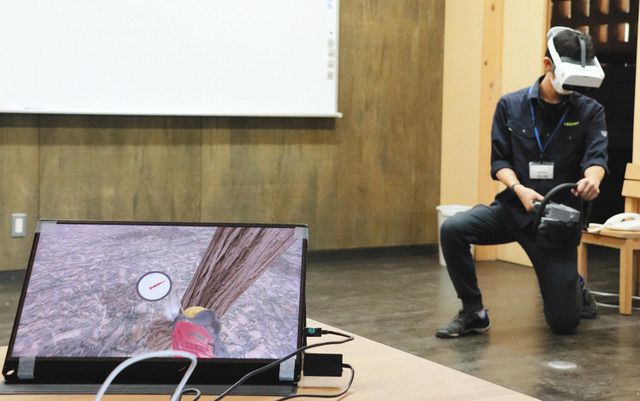 チェーンソーの正しい使い方が学べるＶＲ機械を体験する林業関係者。左下の画面は操縦者が見ている映像＝美濃市曽代の県森林文化アカデミーで