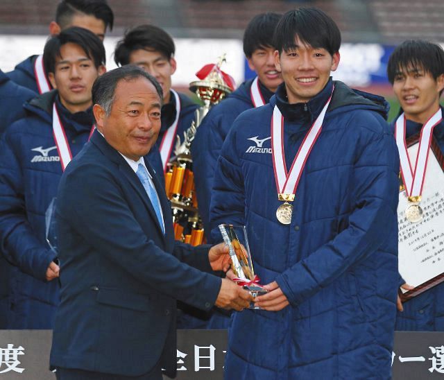 昨年の全日本大学選手権・表彰式で、大会最優秀選手の蓮川壮大（明大）にトロフィーを渡す関東大学連盟の中野雄二理事長（左）＝2019年12月