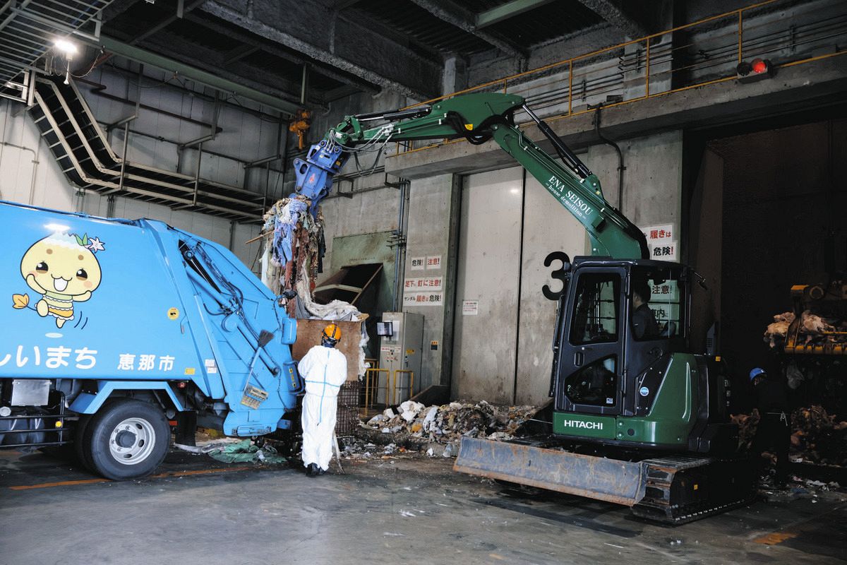 他市で処分してもらうため、ピットからごみを出して収集車に載せる職員ら＝恵那市長島町のエコセンター恵那で