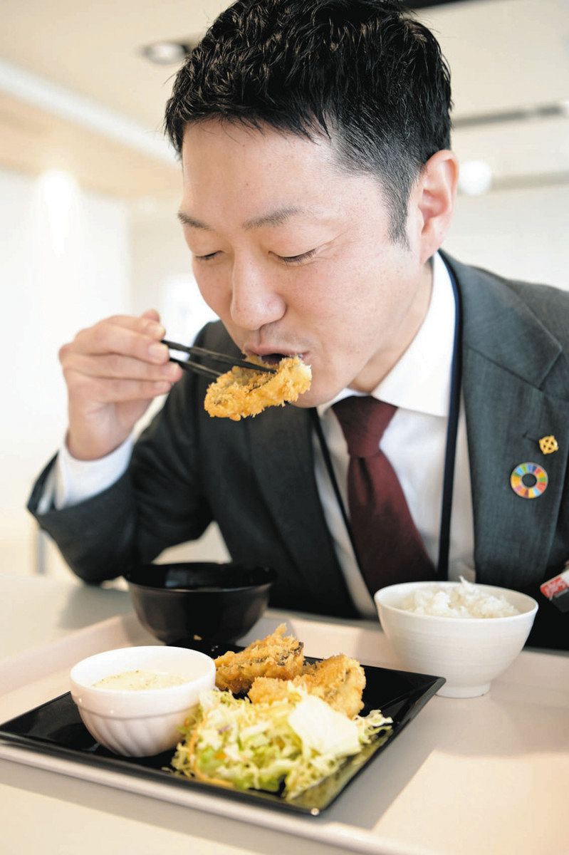 アイゴのフライを食べる原田さん＝津市丸之内で