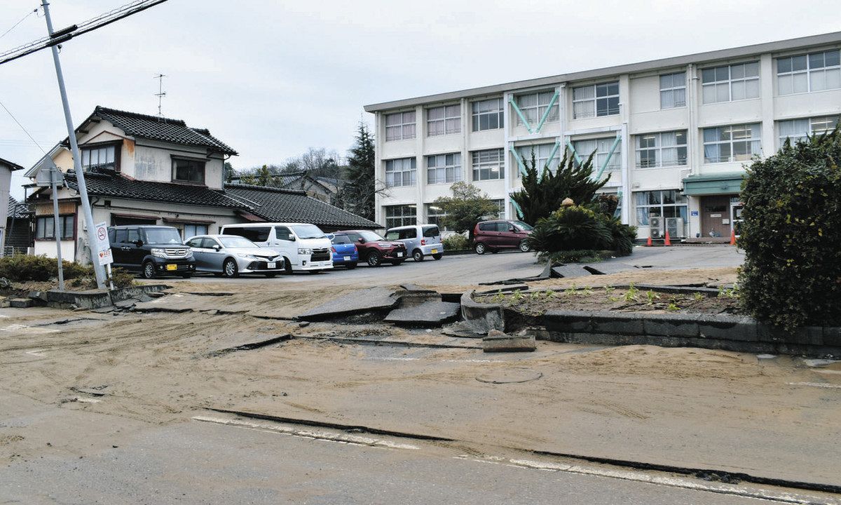 液状化で大きな被害を受けた西荒屋小の校門。右奥は校舎、手前の道路は石川県道松任宇ノ気線＝2024年1月3日、石川県内灘町で（栗田啓右撮影）　