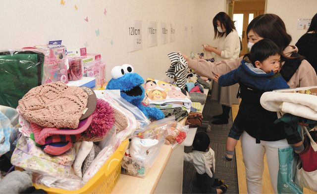 持ち寄られたおもちゃや子ども服を手に取る母親たち=金沢市片町で