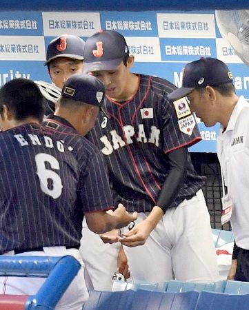 ８月２６日の壮行試合で、１回の投球を終え、仲井コーチに手を見せる高校日本代表の佐々木（中央）