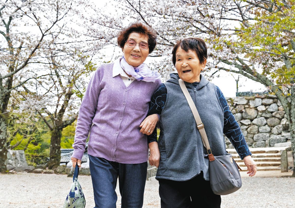 能登半島地震で県外避難していた４月、桜の下で笑顔を見せる木挽サチ子さん（右）と刀祢春子さん＝三重県松阪市で