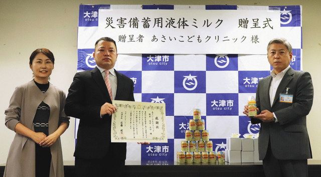 災害時などに役立つ液体ミルクを、大津市に寄贈した浅井院長（中）＝同市役所で 