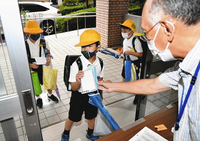 ２学期がスタートし、校内に入る前に検温シートを見せる児童＝金沢市馬場小で 