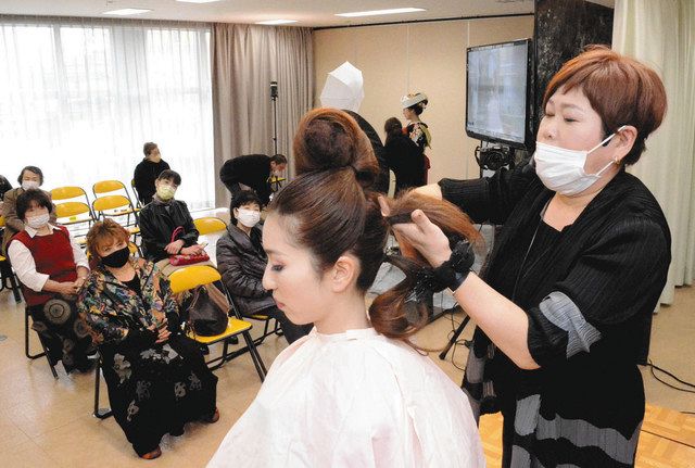 モデルに結婚式用のヘアスタイリングを施す岩田さん（右）＝福井市の県美容会館で 