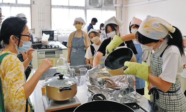 小林代表（左）に教わりながらアルファ米にお湯を注ぐ生徒たち＝豊明市の市共生交流プラザ「カラット」で 