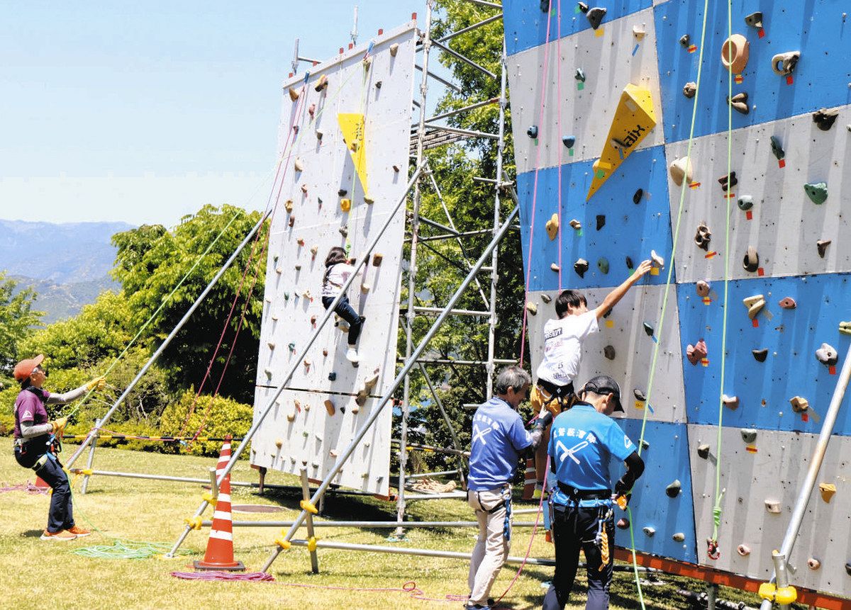 スタッフのサポートのもとでクライミングに挑戦する子どもら＝尾鷲市の県立熊野古道センターで
