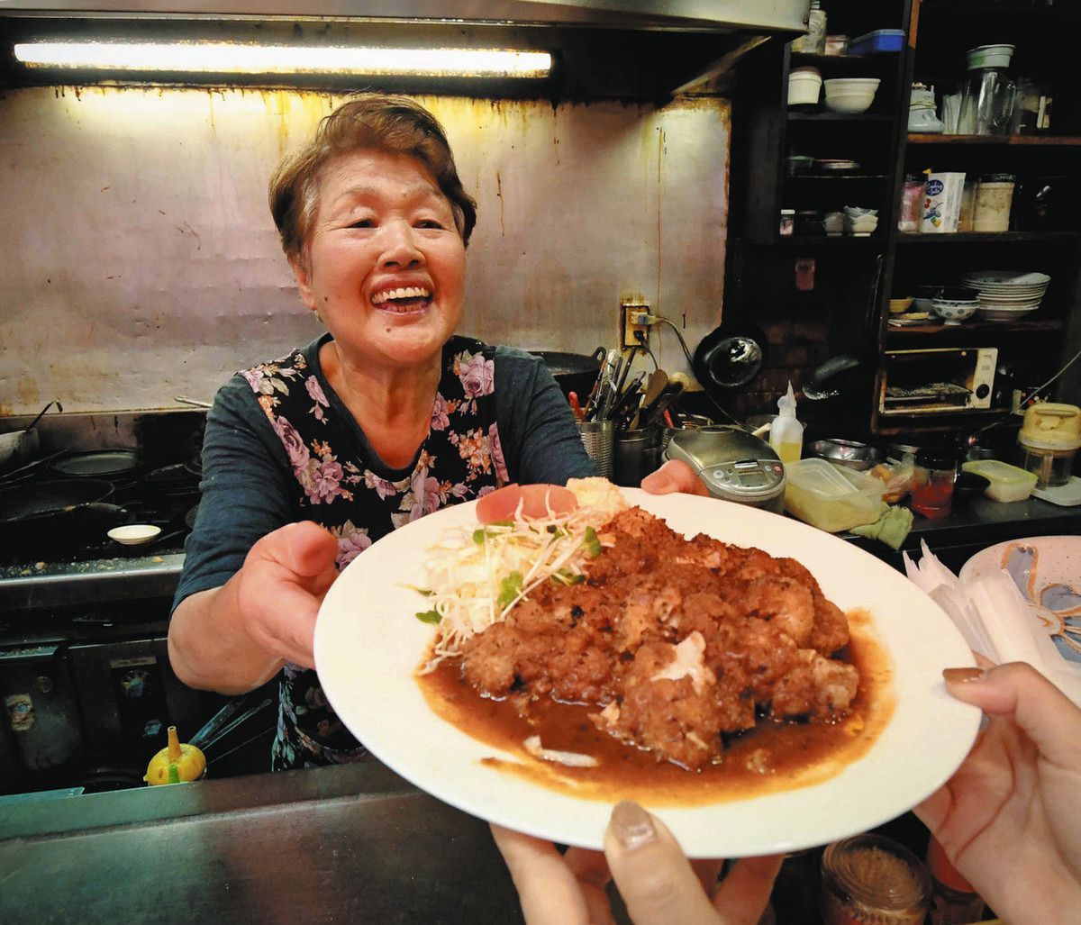 自慢のチキンカツレツを笑顔で提供する田原さん＝津市大門のグリル蛙で