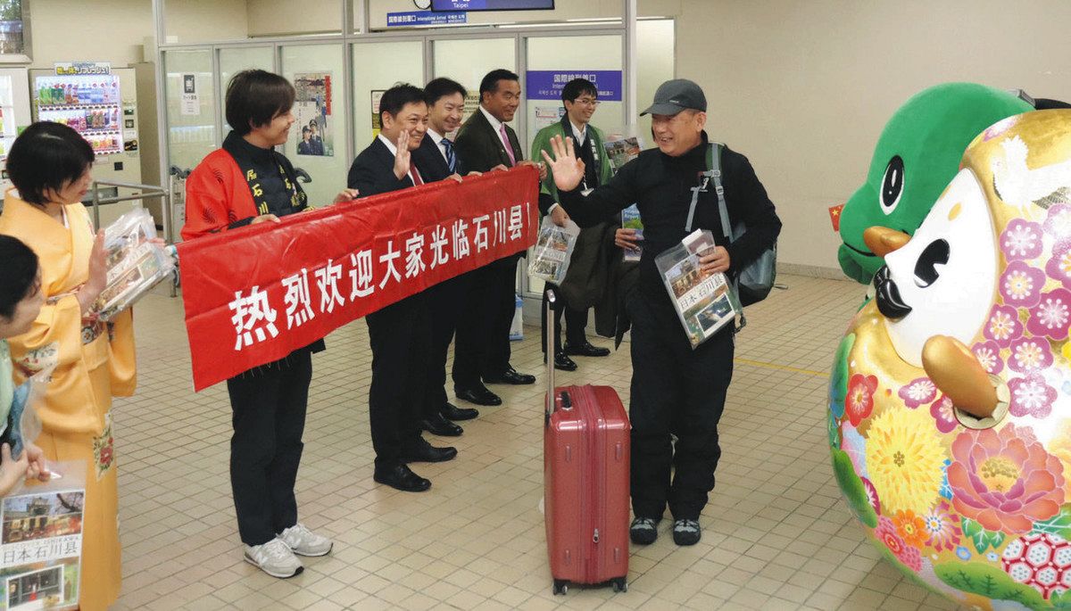 上海からの搭乗客を笑顔で迎え入れる関係者ら＝小松空港で
