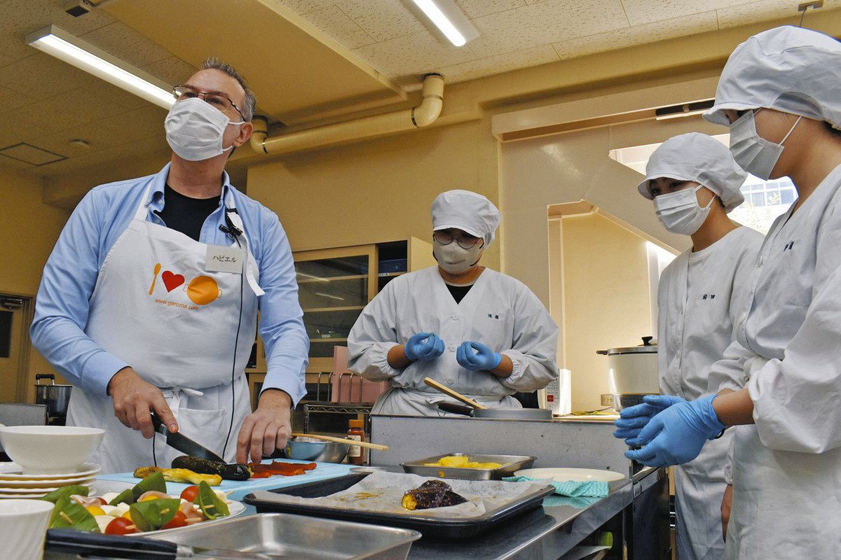 学生らに調理のこつを教えるハビエルさん（左）＝津市一身田中野の市立三重短大で