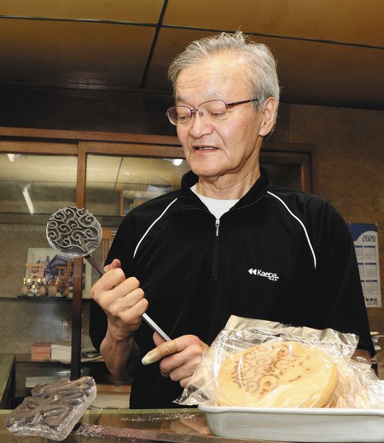 カタパンに刻む唐草模様の焼き印のこてを持つ井村さん＝伊勢市八日市場町の丸与製パンで 