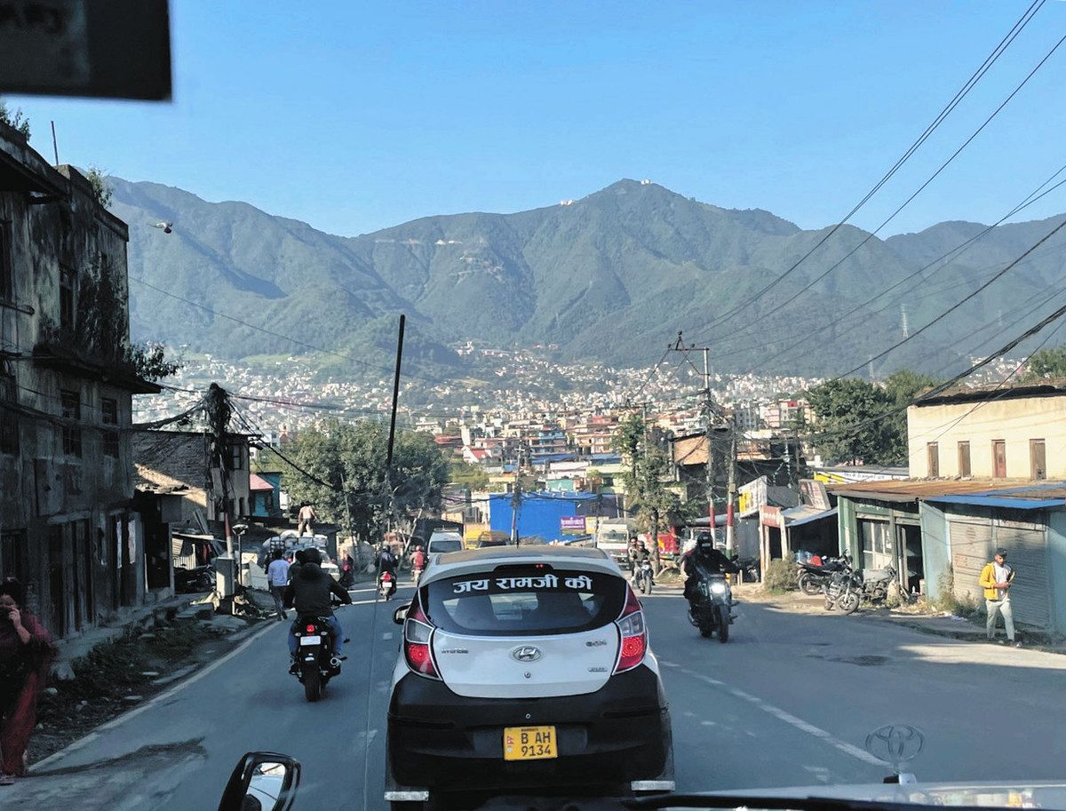 カトマンズ市内の幹線道路。前方の山を越えて険しい道を進むと、その村があった＝ネパールで
