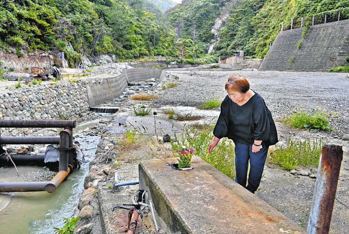 ホテル海楽荘の跡地で、看板が立っていた場所に花を手向けた池田真里子さん＝21日、石川県珠洲市真浦町で