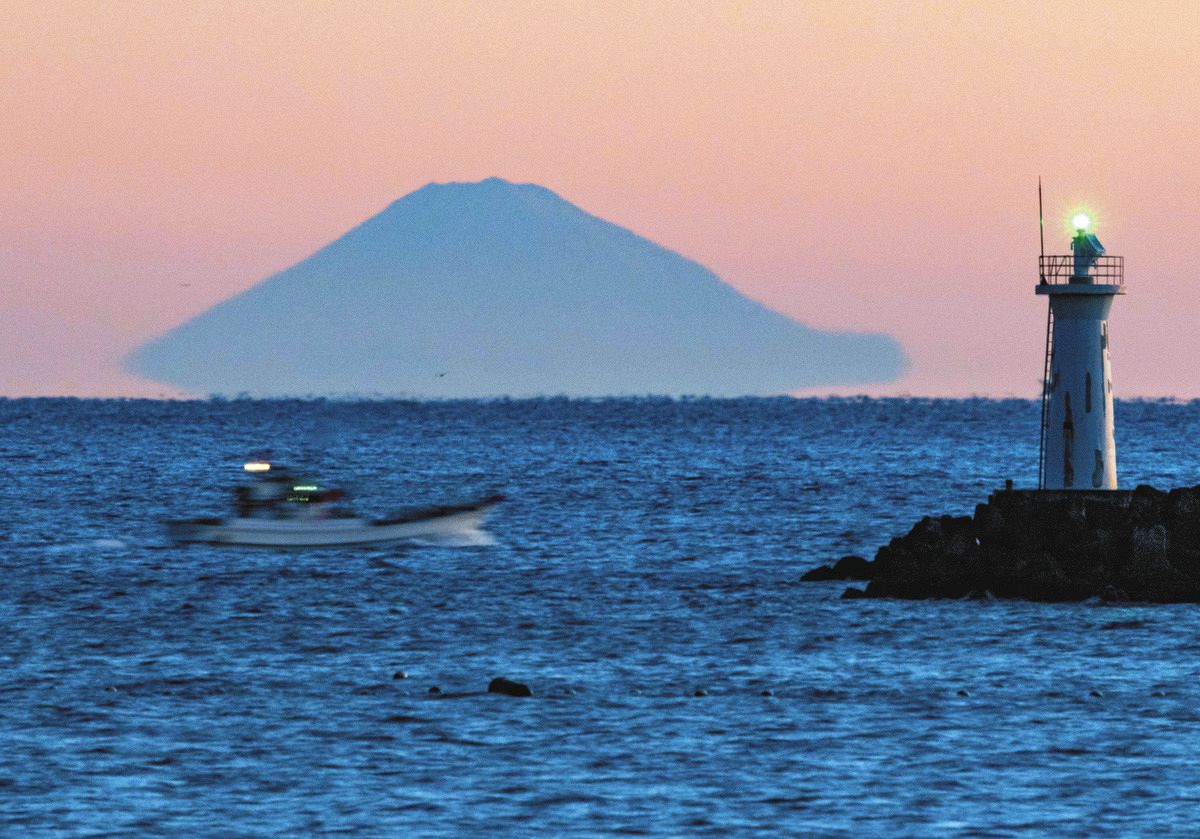 朝焼けの水平線に「浮き富士」現れる 志摩の漁港「ここから眺めるのが
