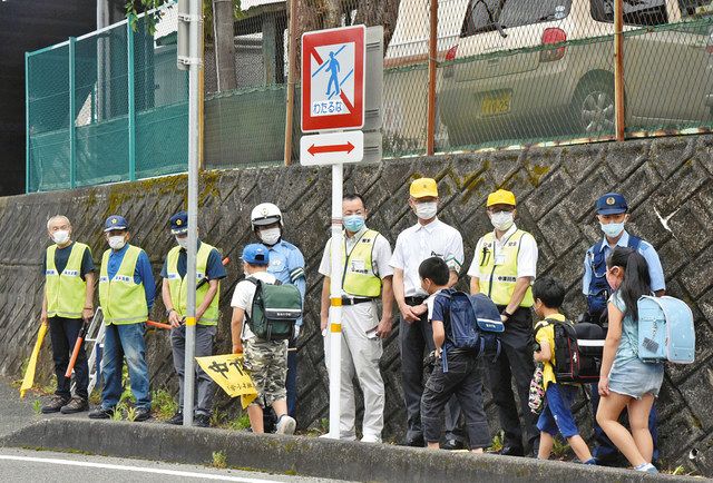 「わたるな」の平仮名表示に変わった標識の前で、児童に安全な道路の渡り方を伝える中津川署員ら＝中津川市千旦林の坂本小前で 