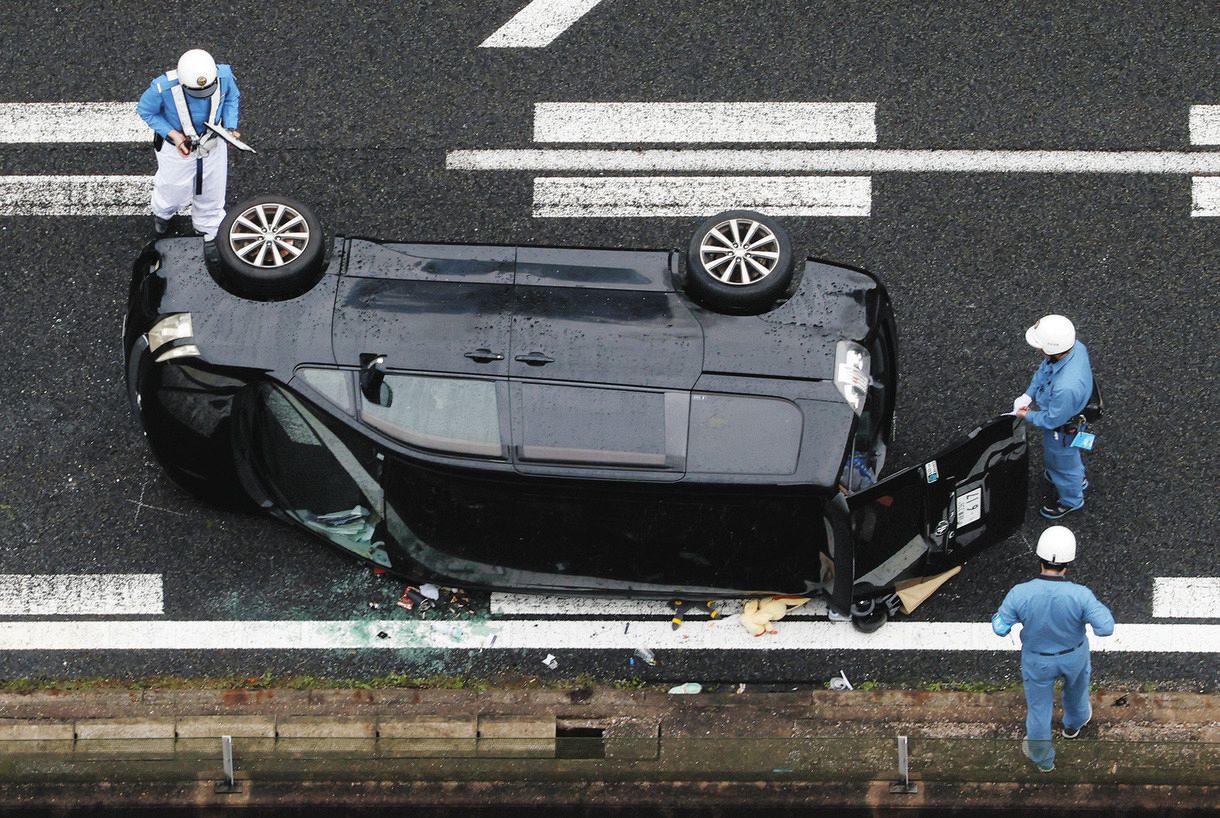 事故で横転した乗用車を調べる警察官＝25日午後、岐阜県瑞浪市で、本社ヘリ「わかづる」から