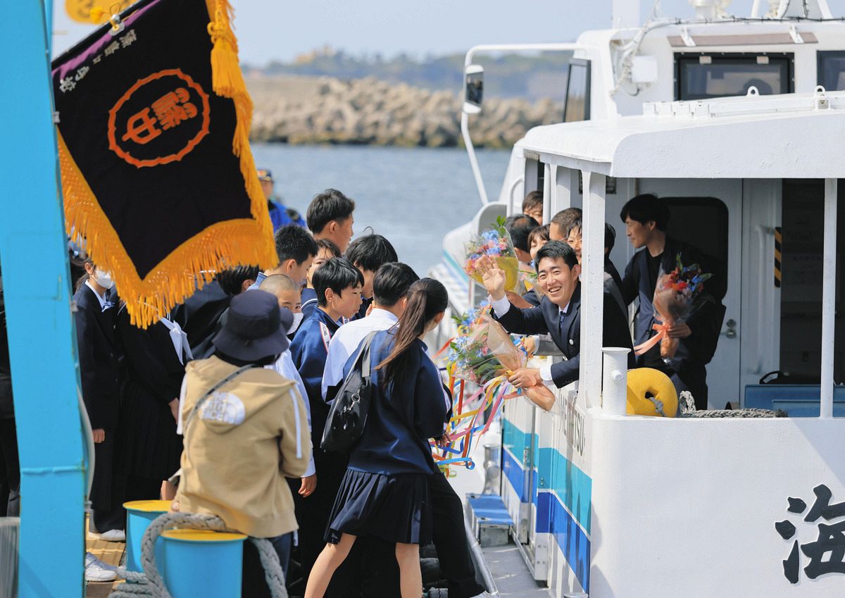 島を離れる船に乗り込み、手を振る水谷有紀先生（手前右）。桟橋には生徒が見送りに訪れた