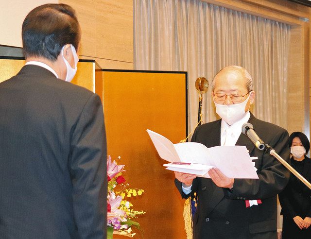 記念事業の目録を手渡す飯貝恵秀会長（右）＝加賀市柴山町で 