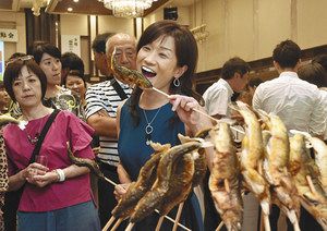 「清流めぐり利き鮎会」でアユの塩焼きを食べる参加者＝１３日午後、高知市で