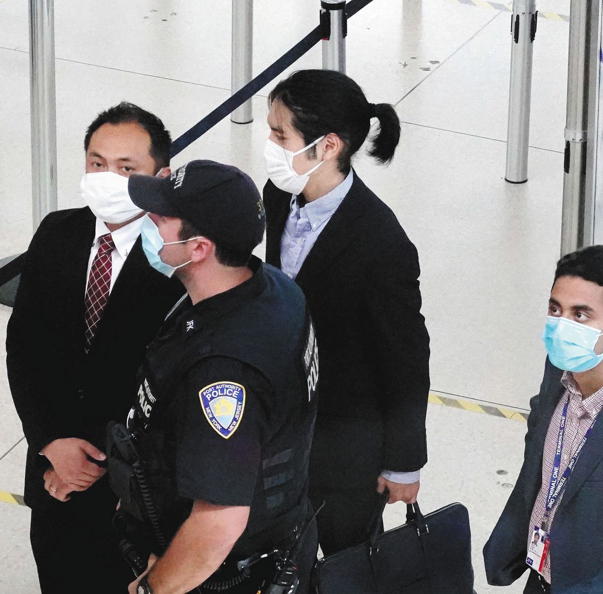 米ニューヨークのケネディ国際空港で、空港職員に囲まれながらセキュリティーチェックに向かう小室圭さん（左から３人目）＝２６日（共同）