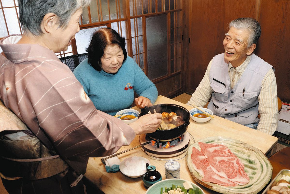 自らが育てた「もりやま」号の肉をかみしめ、満面の笑みを見せる森本武治さん（右）と妻の照美さん（中）＝松阪市飯南町深野で
