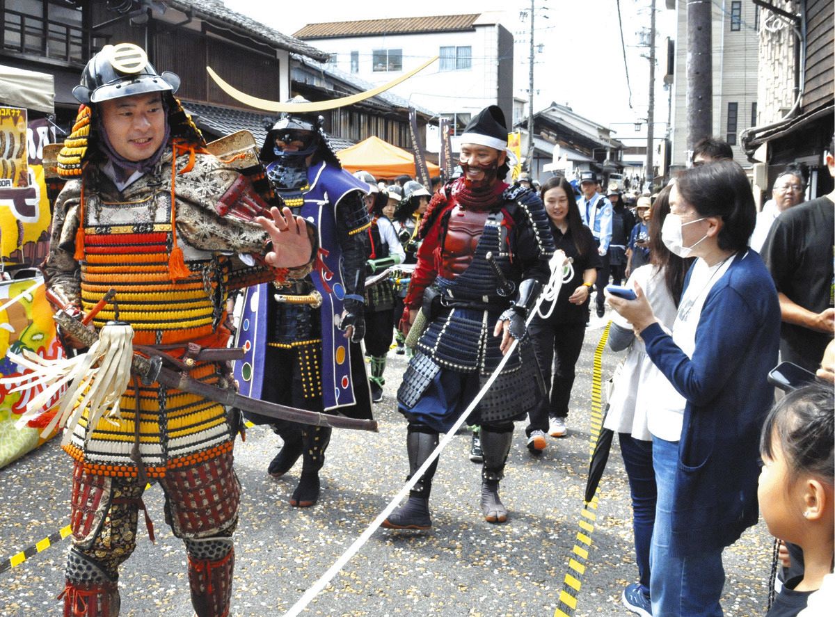 沿道の人たちに手を振りながら行進するあばれる君（左）＝中津川市本町の中山道で