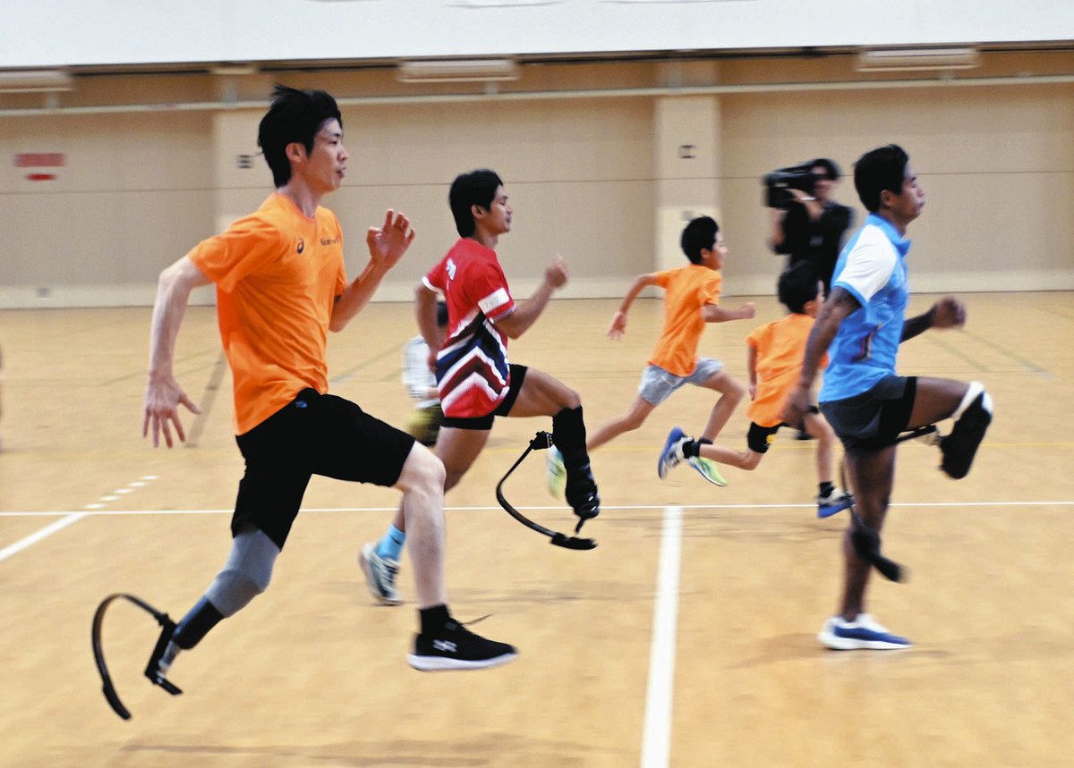 アジアパラ大会に出場した選手と一緒にスポーツ用義足で走る参加者ら＝豊田市のトヨタスポーツセンターで
