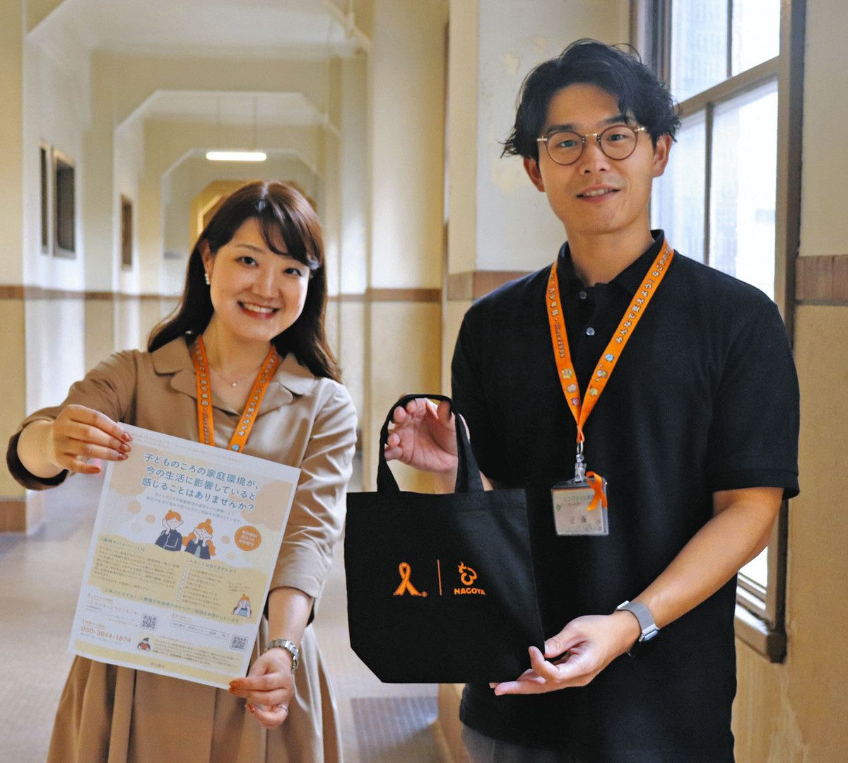 相談窓口のちらしや啓発グッズを手にする市の担当者＝市役所で
