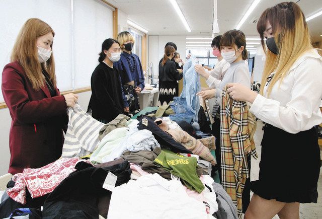 廃棄される服の山からドレスの材料を選ぶ生徒たち＝金沢市竪町で 