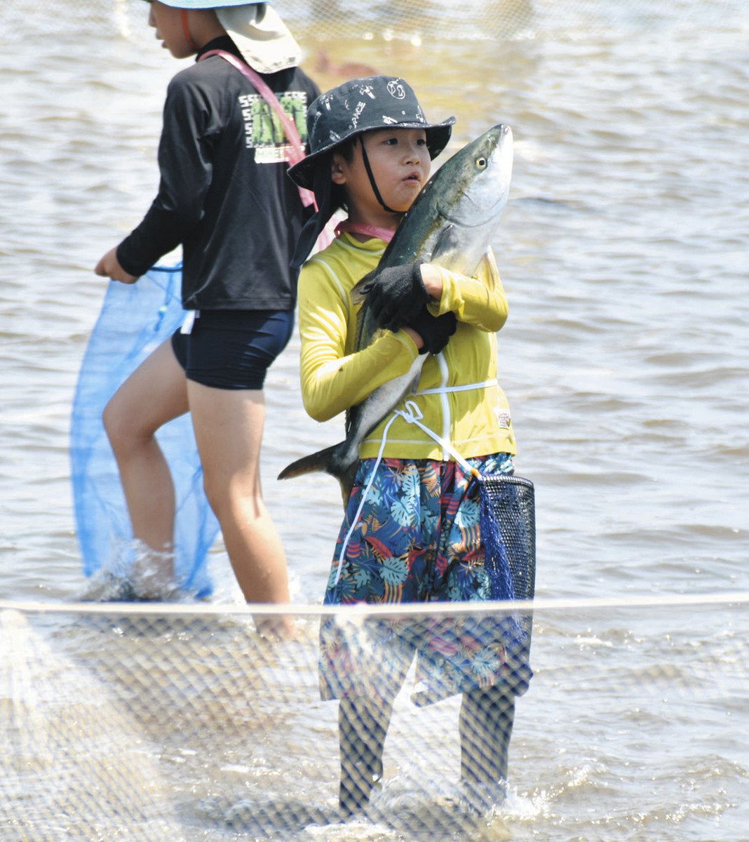 つかみ取った大きな魚を抱きかかえる子ども＝津市の御殿場海岸で

