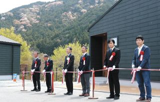 コテージのオープンを祝し、テープカットに臨む竹上市長（左から3人目）ら＝松阪市飯高町宮前の道の駅「飯高駅」で