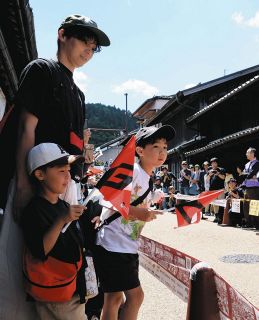 古い町並みで、旗を手にラリーカーの通過を待つ子どもたち＝恵那市岩村町で