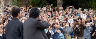 仲野太賀さん（手前左）と小栗旬さん（手前右）に手を振る大勢の人たち