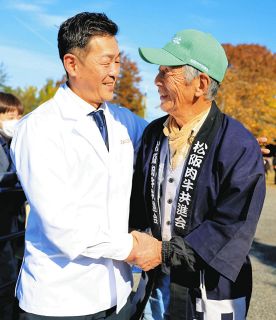 「みすとし5」号を競り落とした「牛追道中」の黒岩さん（左）と握手する森本さん＝松阪市伊勢寺町で
