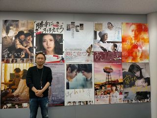 コンテンツプロデュースで手掛けた珠玉の映画作品のポスターの前に立つ名古屋テレビ（メ～テレ）の服部保彦部長