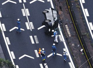事故で横転した乗用車を調べる警察官＝25日午後、岐阜県瑞浪市で、本社ヘリ「わかづる」から