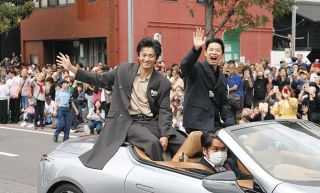 オープンカーに乗り込み、沿道の人たちに手を振る俳優の小栗旬さん（左）、仲野太賀さん