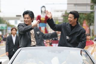 オープンカーに乗り込み、沿道の人たちに手を振る俳優の小栗旬さん（左）、仲野太賀さん。後方はナナちゃん隊